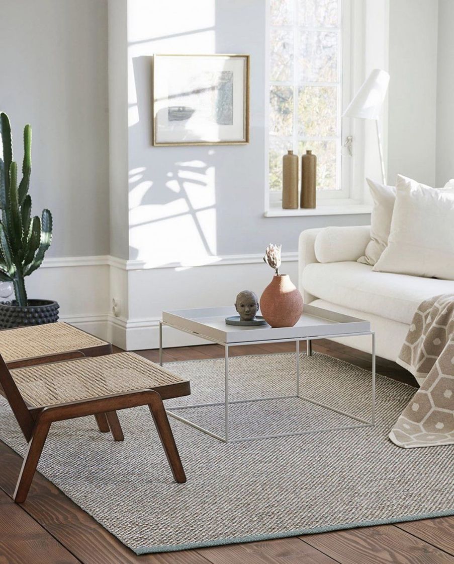 A living room with a light sofa, cushions and shelves, in the Scandinavian Design showroom style